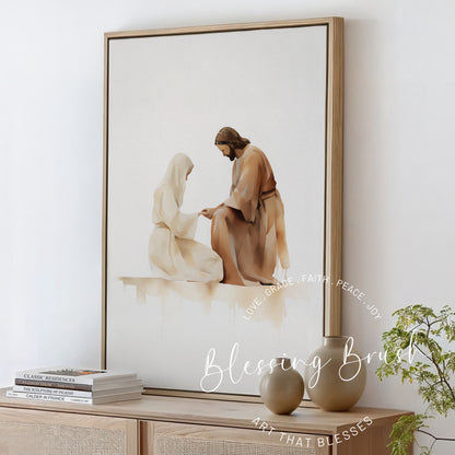 Watercolor painting of Jesus kneeling before a woman, holding her hands in a gentle moment of healing and compassion, framed Christian wall art in neutral tones, Blessing Brush.